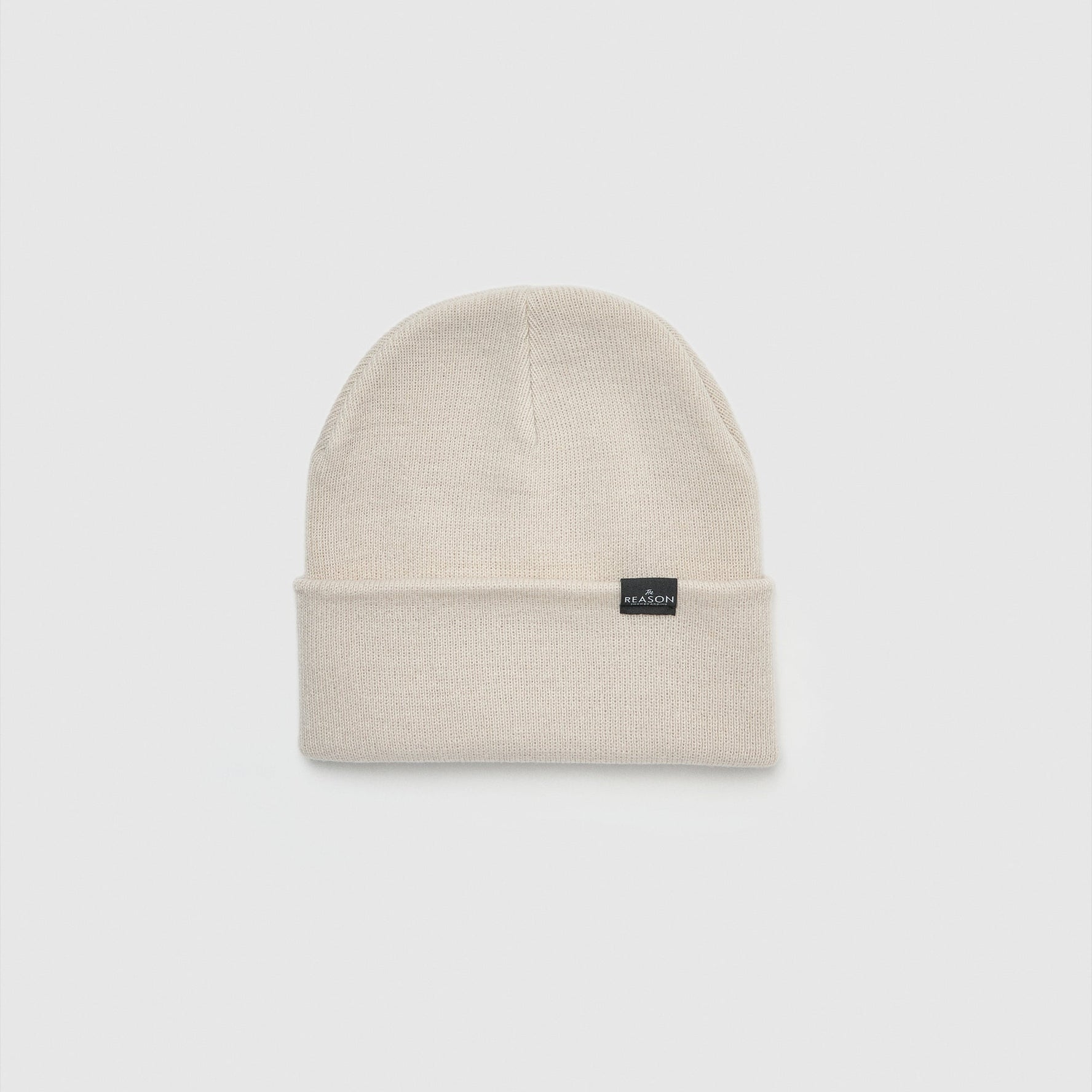 Beige beanie with a small black label on a light gray background